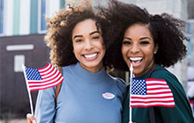 two smiling woman holding small American flags