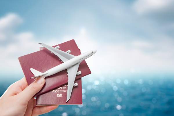 model airplane and passports held in front of ocean