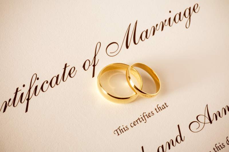 wedding rings rest on marriage certificate